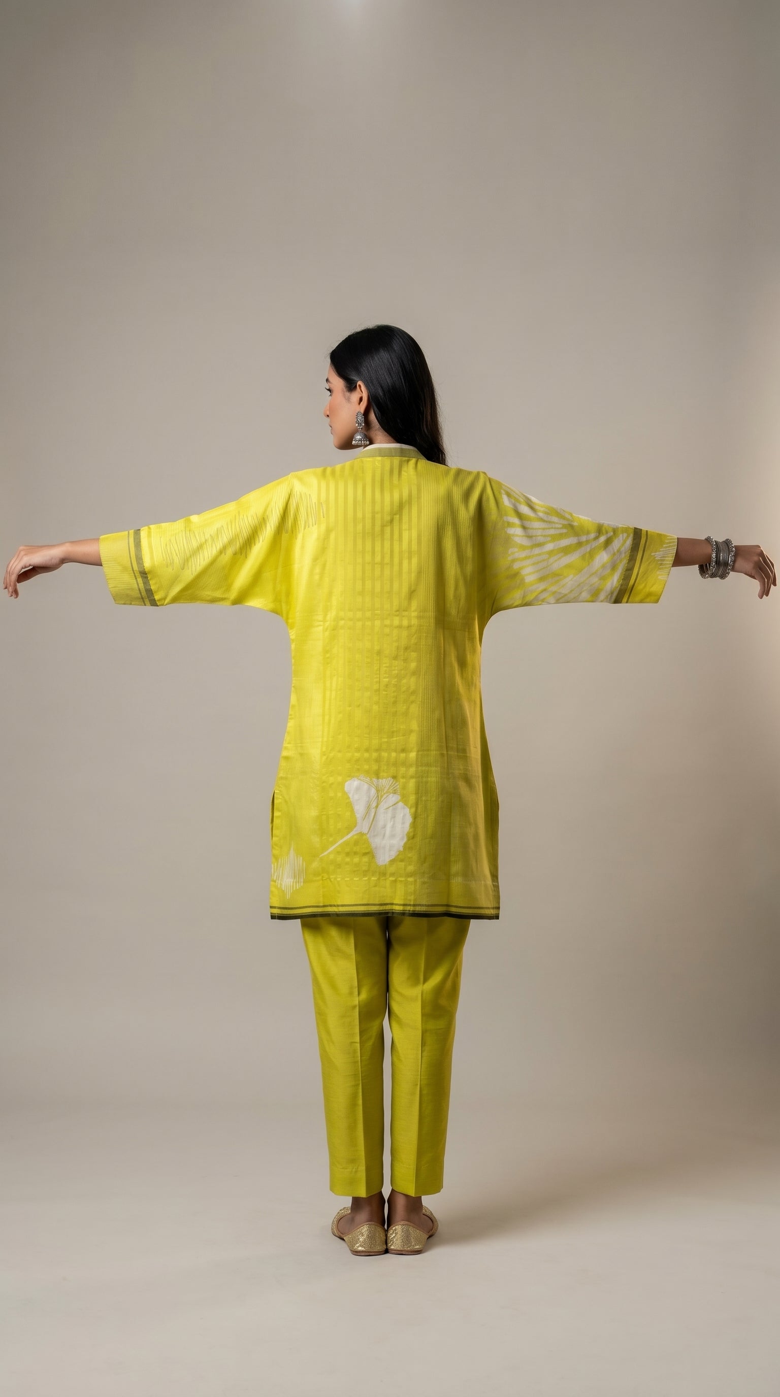 Woman wearing a bright green traditional outfit with white patterns on a beige background