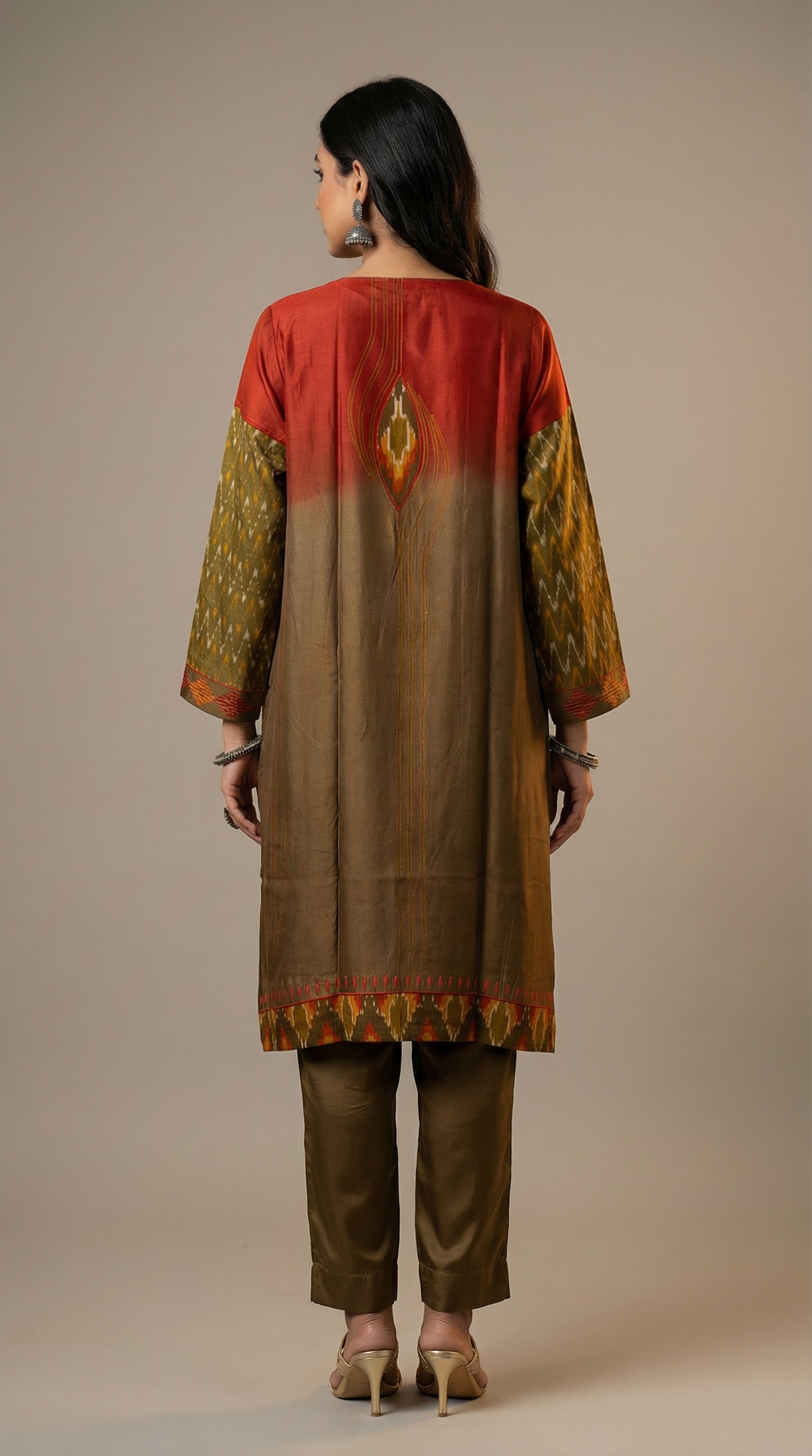 Woman wearing a traditional kurta with a red and gold and brown pants on a beige background
