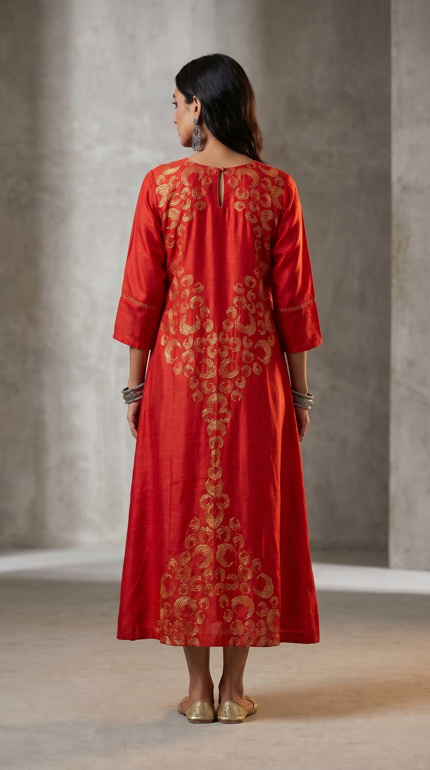 Woman wearing a red embroidered dress against a neutral background