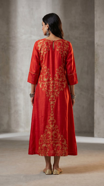 Woman wearing a red embroidered dress against a neutral background