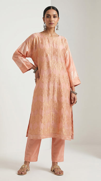 Woman wearing a peach kurta with pants on a white background