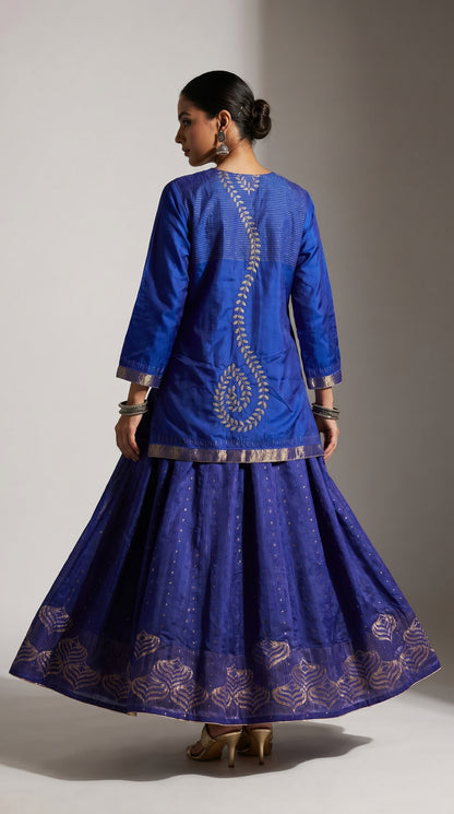 Woman wearing a blue embroidered traditional skirt set on a plain background