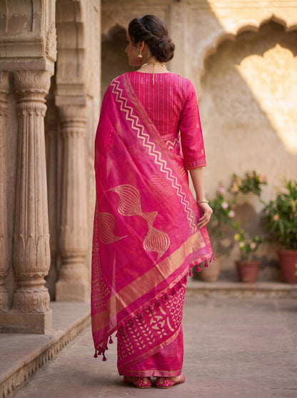 Woman wearing a pink saree with intricate patterns in an outdoor setting.
