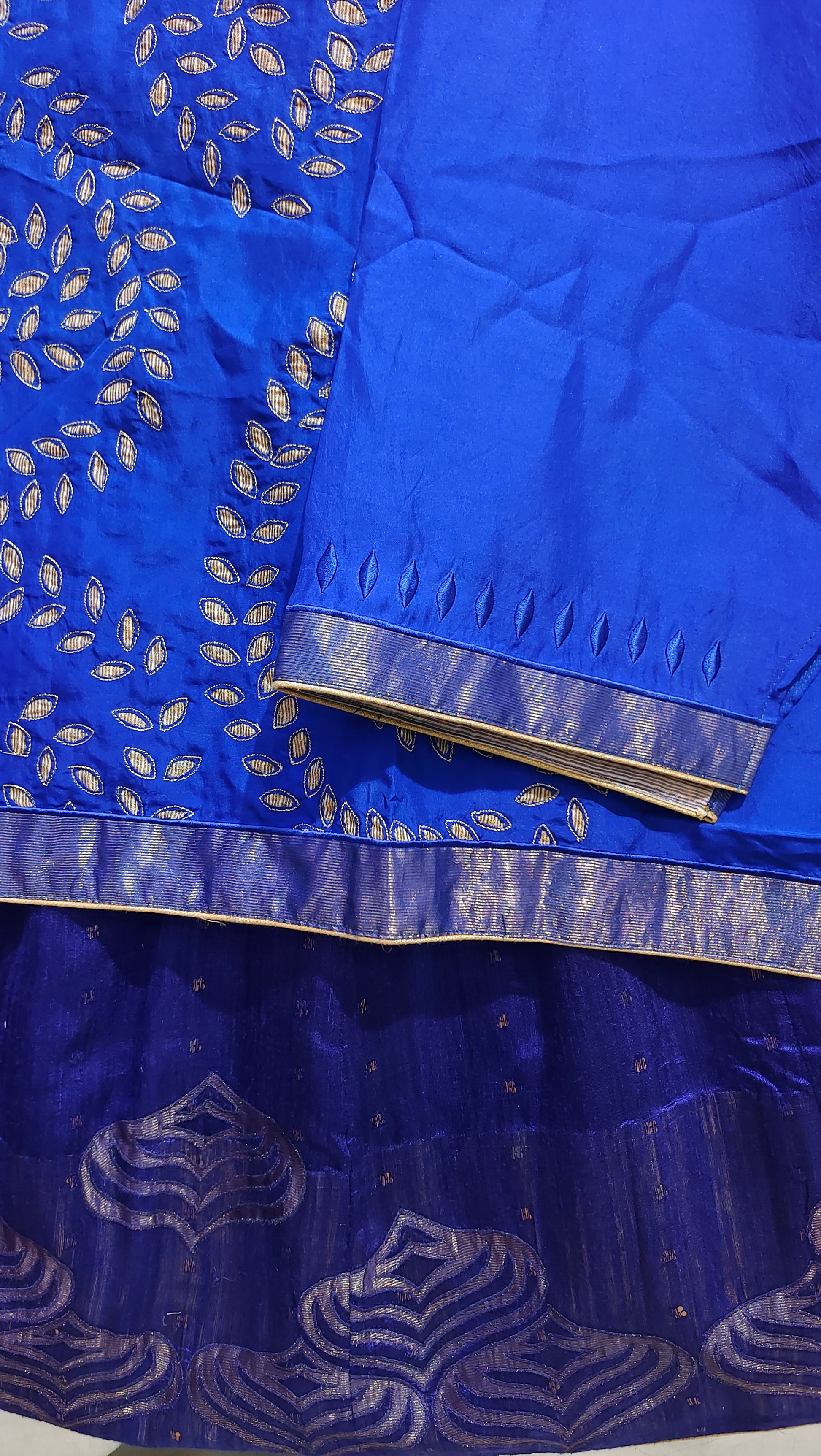 Close-up of a blue fabric with gold patterns and a metal object on a white background