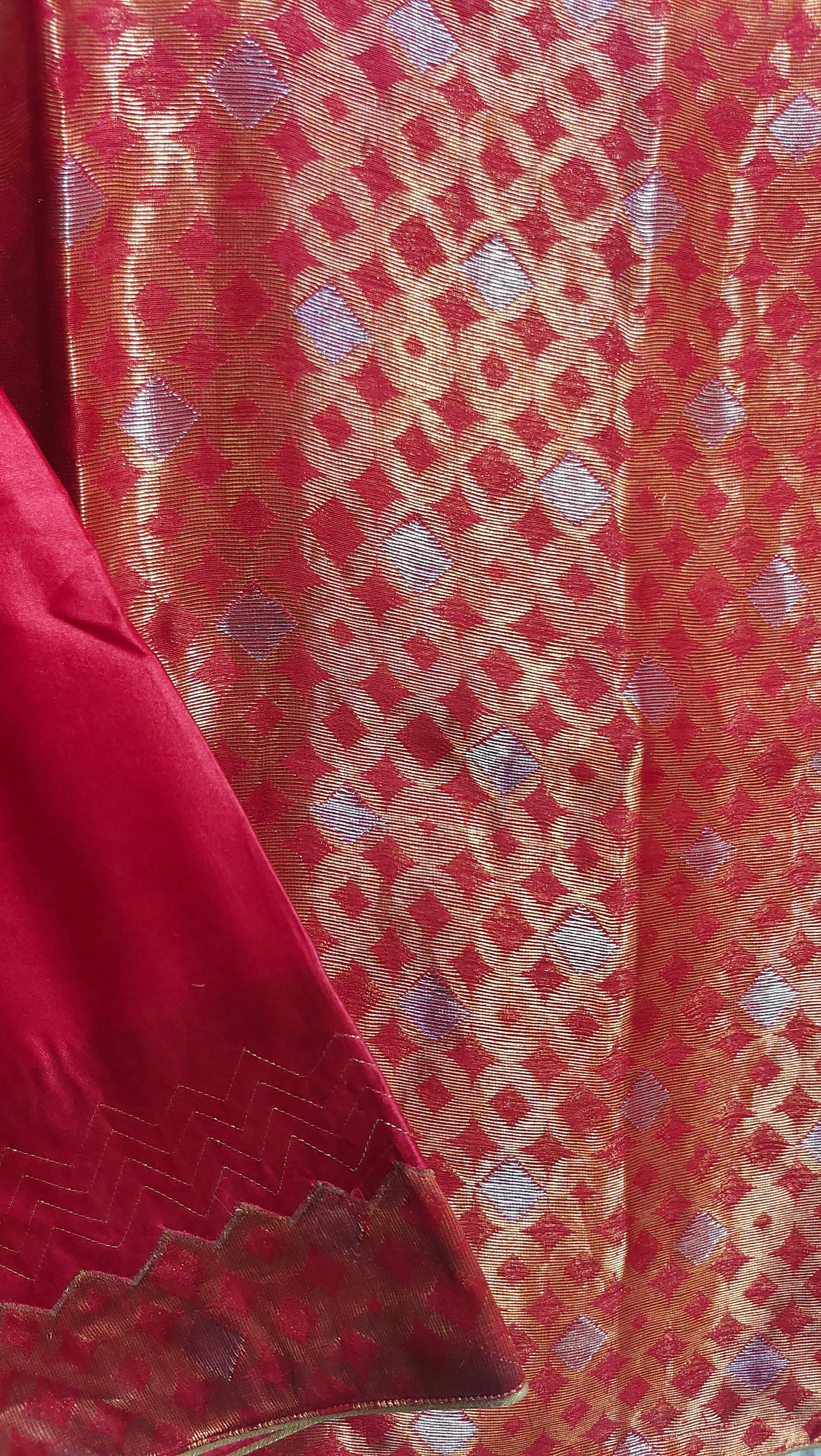 Close-up of red fabric with intricate gold and silver pattern