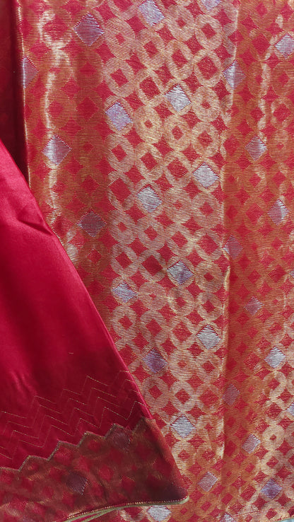 Close-up of red fabric with intricate gold and silver pattern