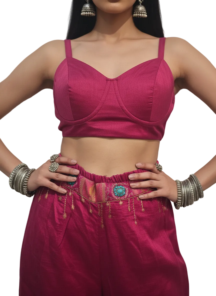 Woman wearing a pink top and plazzo pants with floral elements on a white background