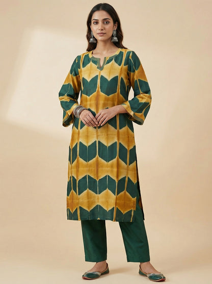 Woman wearing a green and yellow patterned kurta with trouser pants on a beige background