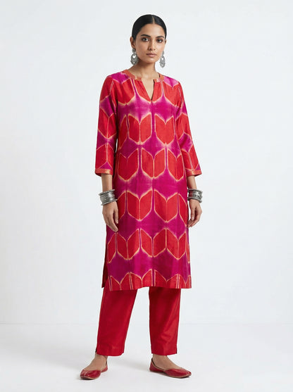 Woman wearing a red and pink patterned kurta with pants on a white background